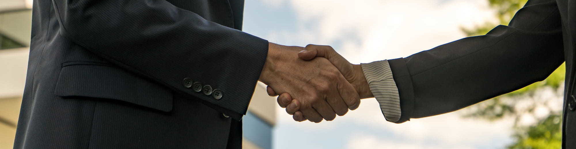 Two businesspeople shaking hands - Contact Us | Amarex