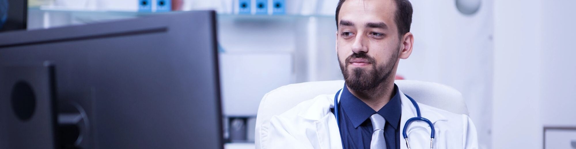 Doctor working on his computer in cabinet 126872476