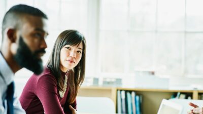 Businesswoman listening to colleague present about pharmacovigilance meeting 935644250