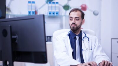 Doctor working on his computer in cabinet 126872476