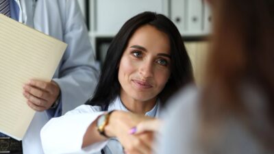 Smiling female doctor shaking hands with clinical visitor 131226435